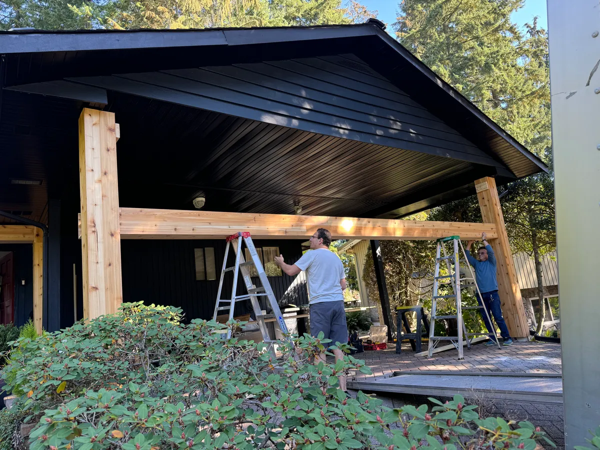Workers securing the header beam across porch columns
